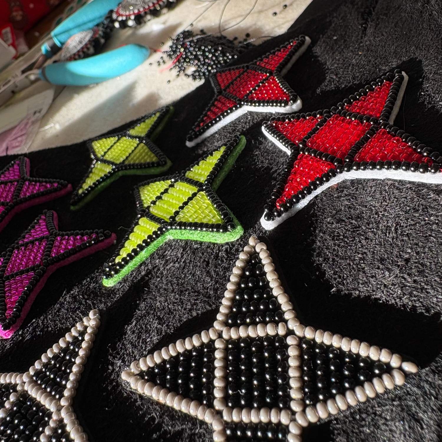 Collection of star-shaped beaded earrings with different colors and designs on a textured surface.
